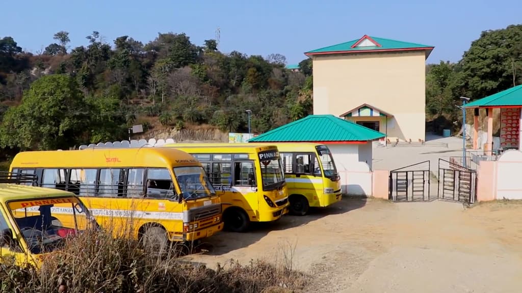 The school gate and building, with the buses parked in the yard