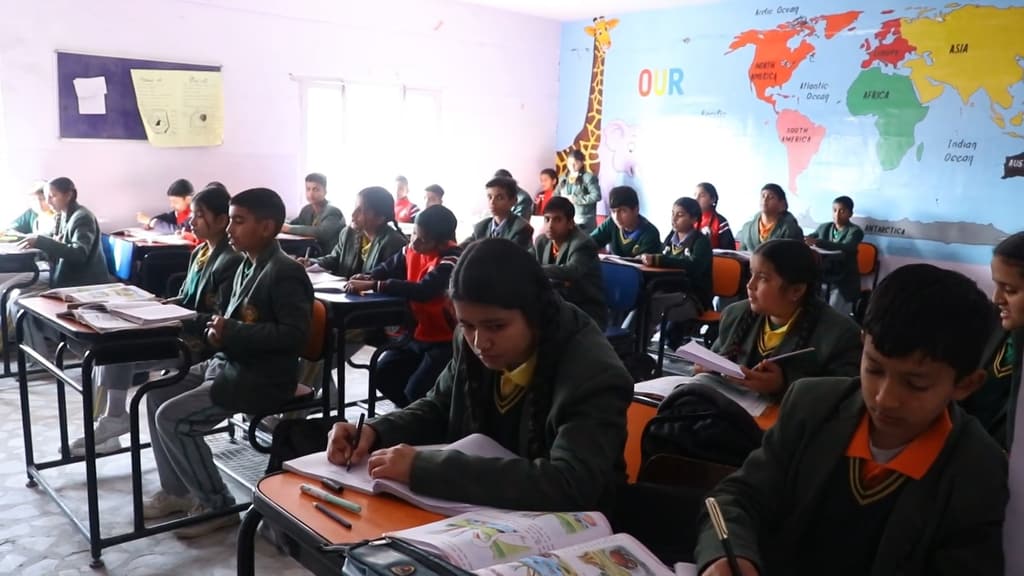 Senior students writing at their desks, with a world map painted on the wall